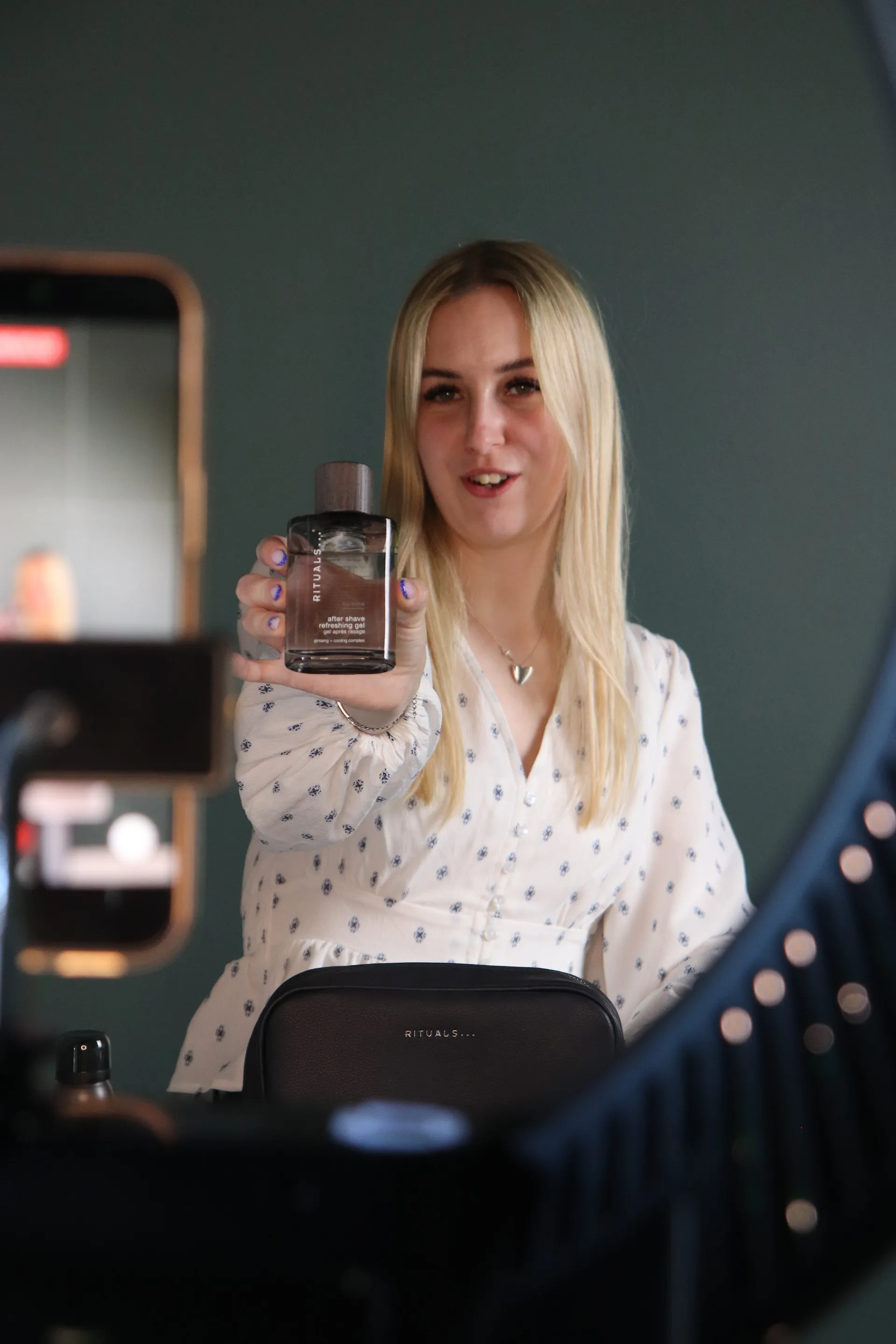 Vært holder en after shave-gel frem mens telefonen streamer live