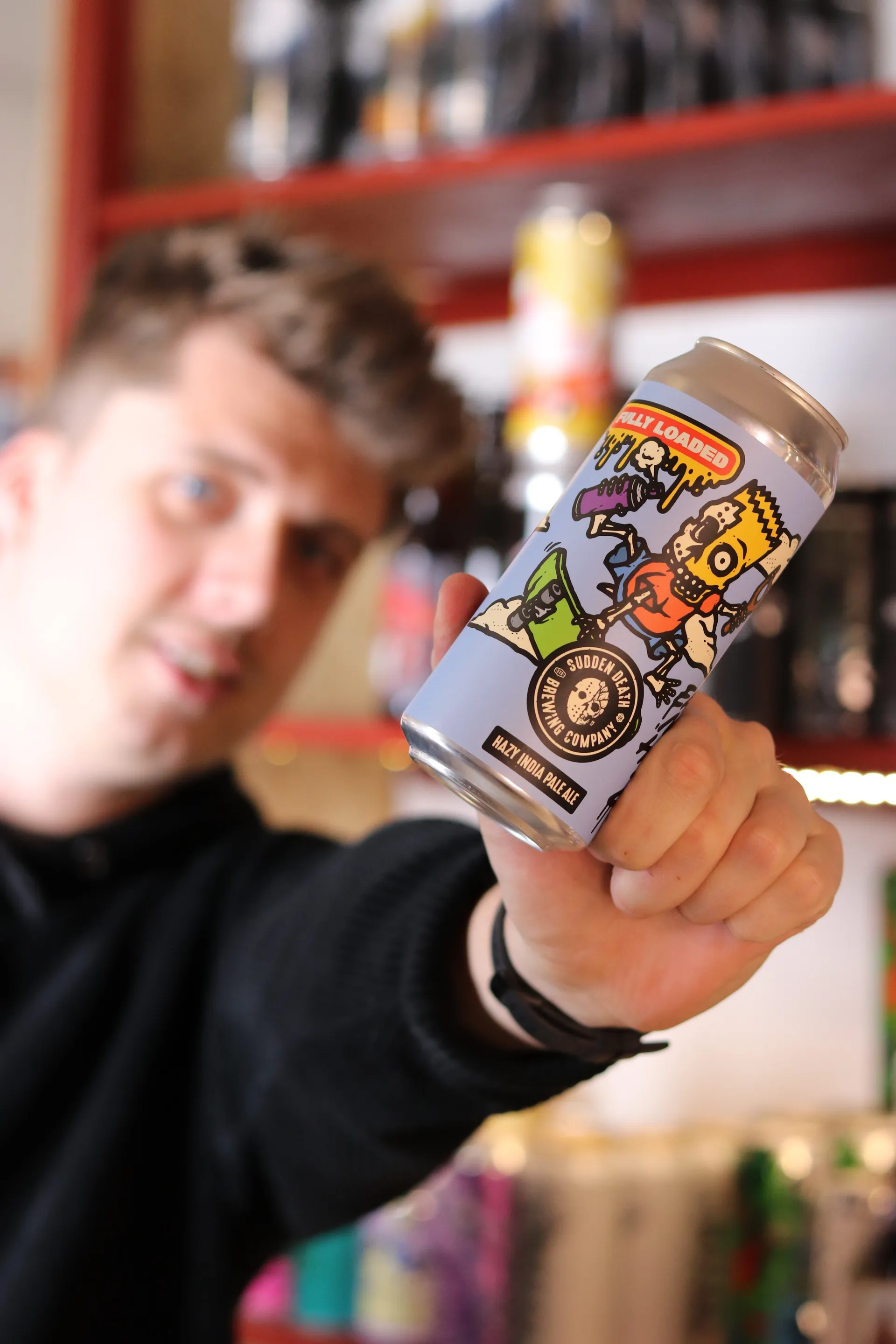Ølhandler rækker en Hazy IPA-dåse mod kameraet under et live show