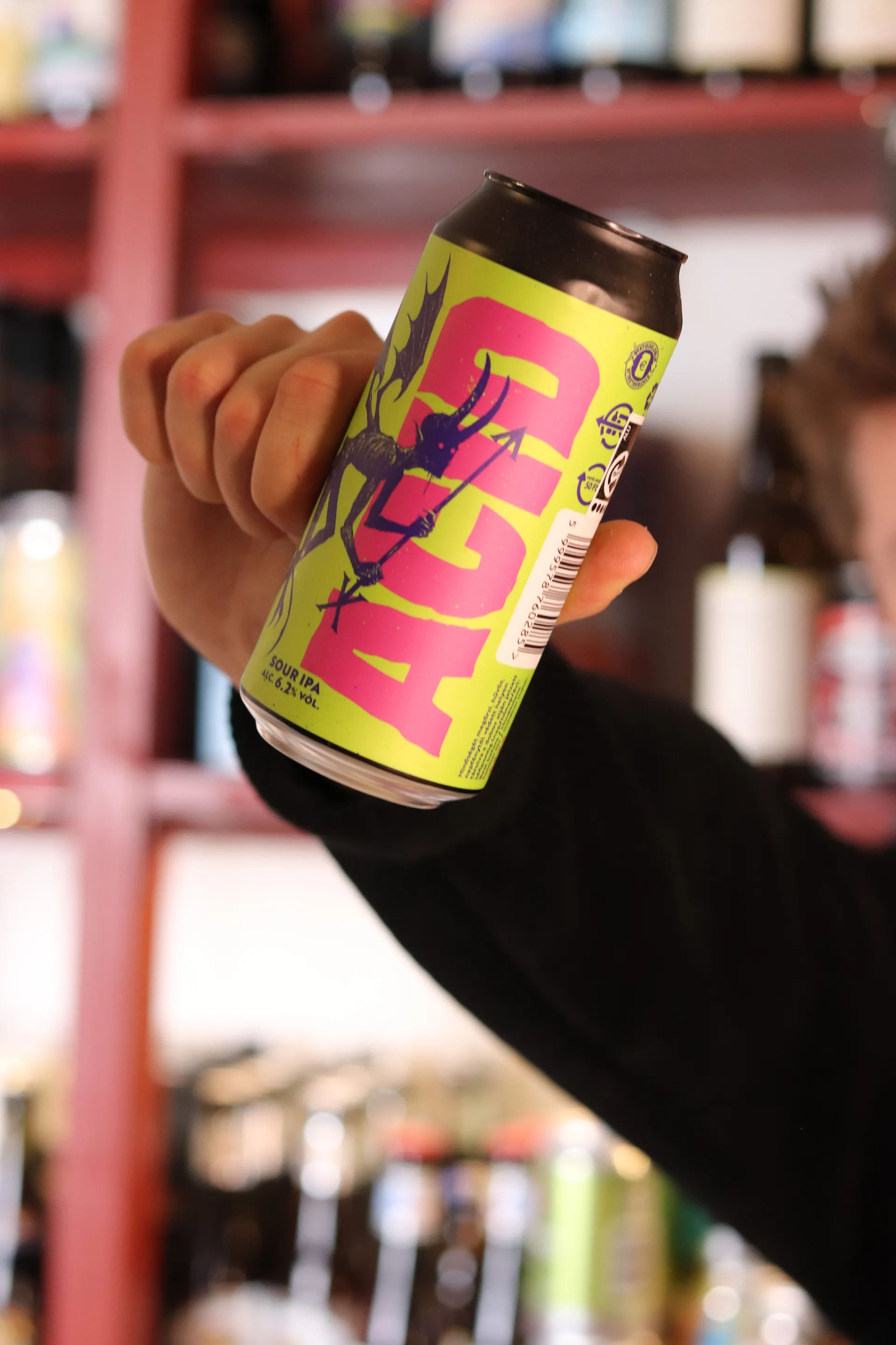 Close-up af Acid Sour IPA-dåse holdt op mod kameraet foran ølreol