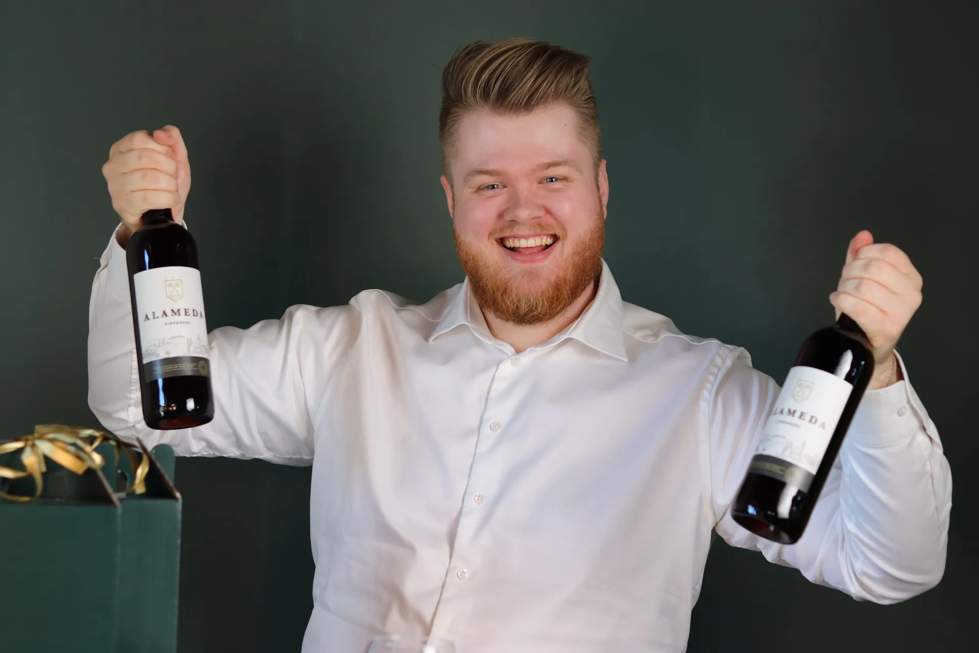 Vinhandler ler med armene oppe og en flaske i hver hånd under live show