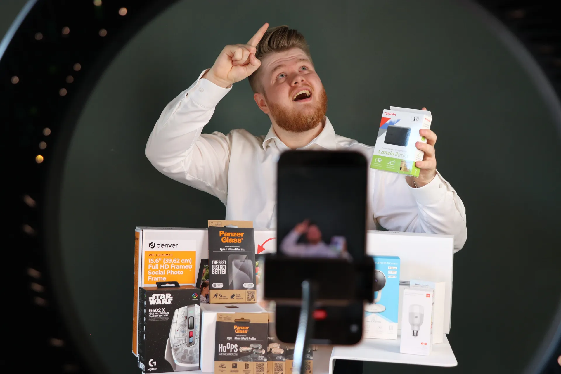 Vært præsenterer et produkt live med telefon og ringlys foran sig