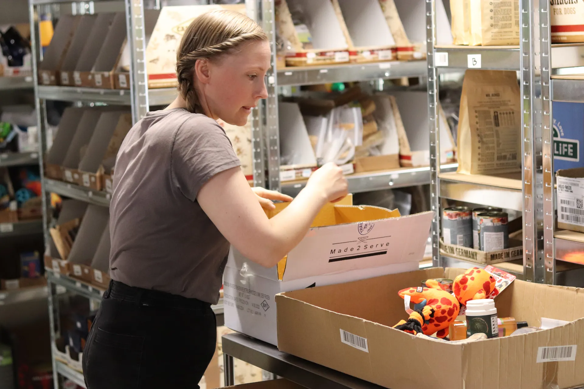 Butiksindehaver pakker en kasse med kæledyrsprodukter til afhentning